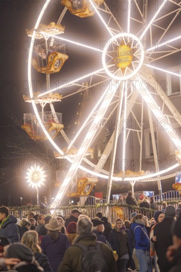An illuminated Ferris wheel lights up the night above a busy Christmas market, Weihnachtsmark Nagold, LandkreisCalw, Germany