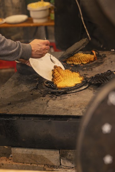 A person picks waffles baked fresh at a market from an oven, Weihnachtsmark Nagold, LandkreiScalw, Germany