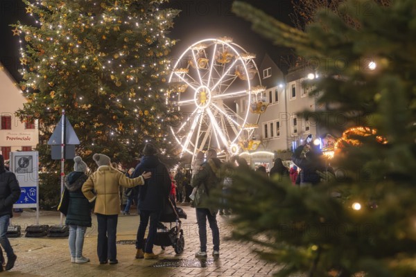 People enjoy the Christmas atmosphere with tree and Ferris wheel at night, Weihnachtsmark Nagold, LandkreiScalw, Germany