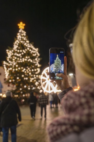 A Christmassy tree is photographed by a person with a mobile phone, Weihnachtsmark Nagold, LandkreisCalw, Germany