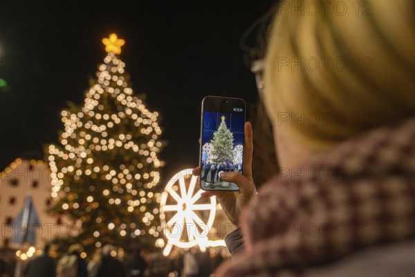 A person photographs a festively illuminated Christmas tree at night, Weihnachtsmark Nagold, LandkreisCalw, Germany