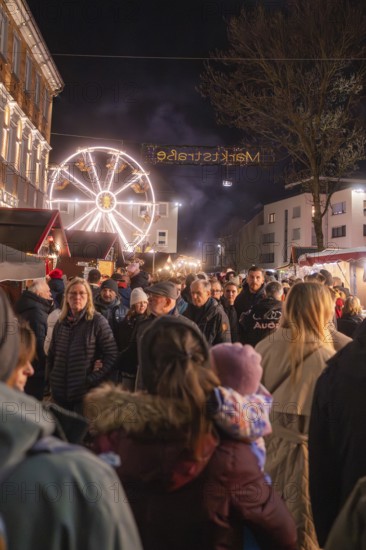 Visitors at a busy night market with illuminated Ferris wheel in the background, Weihnachtsmark Nagold, LandkreiScalw, Germany
