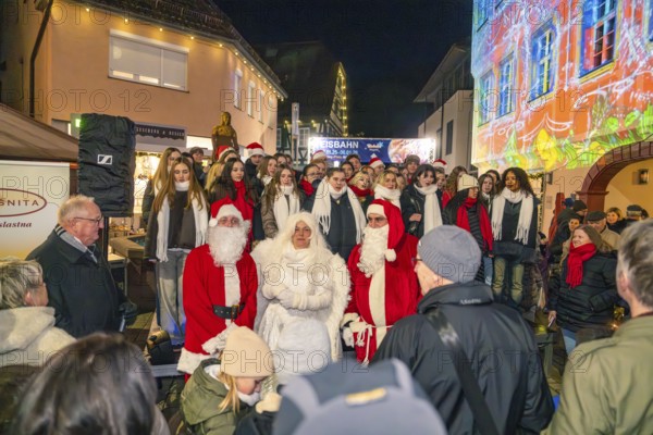 People wearing Christmas costumes at a night outdoor party surrounded by colorful lights, Weihnachtsmark Nagold, LandkreisCalw, Germany