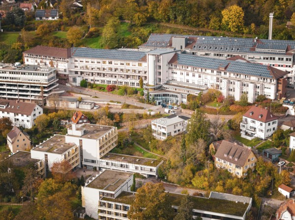 Close-up of buildings with solar panels and surrounding autumn trees in an urban landscape, Altes Krankenhaus, Calw, Germany