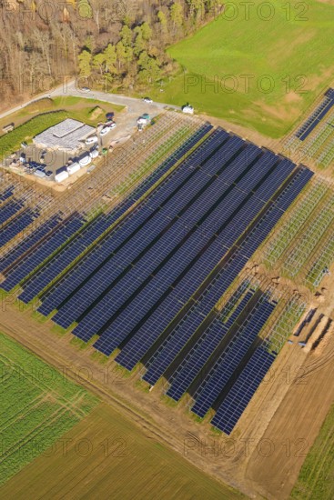 Aerial view of a large solar plant surrounded by autumn trees and fields, energy revolution, construction of PV open space, Baden-Württemberg, Germany