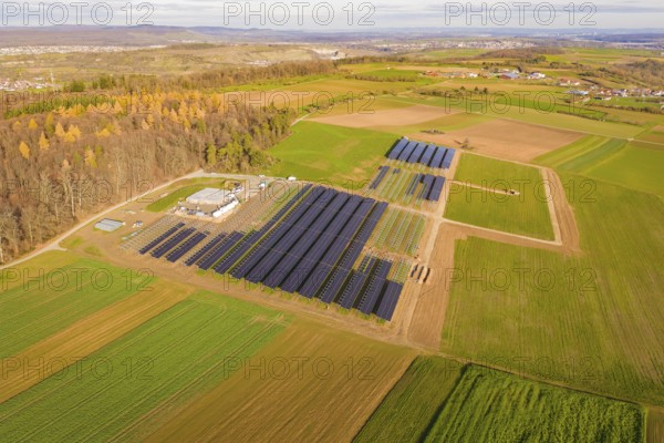 Large solar plant surrounded by autumnal fields and a village in the background, Energiewende, construction of PV open space, Baden-Württemberg, Germany