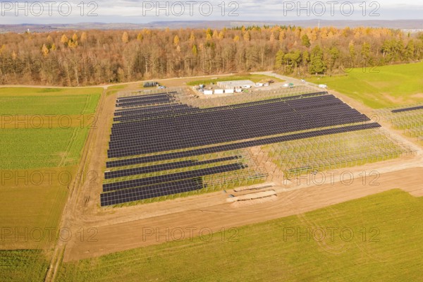 Aerial view of a solar park surrounded by fields and autumn forest, energy revolution, construction of PV open space, Baden-Württemberg, Germany