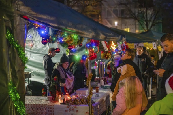 Colourful and festively decorated stands at a Christmas market with many visitors, Christmas market, Aidingen, Germany