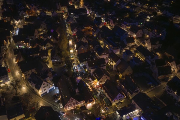Drone image of an illuminated city at night with visible streets and alleys, Christmas market, Aidingen, Germany
