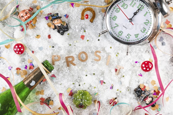 Letters cheers in the snow surrounded by lucky charms, watch and champagne bottle, New Year's Eve