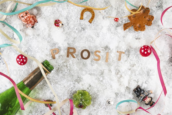 Cheers in the snow surrounded by lucky charms and champagne bottle, New Year's Eve