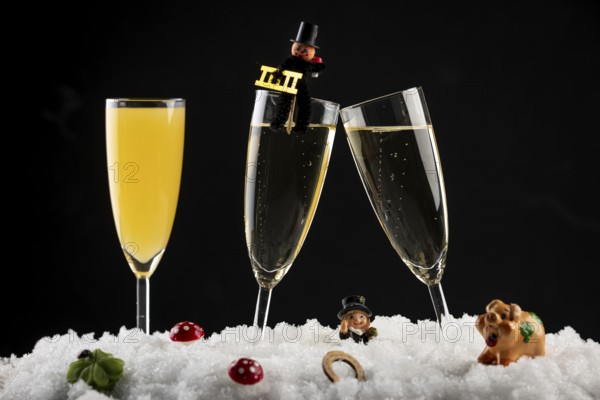 Three champagne glasses with lucky charms for New Year in the snow