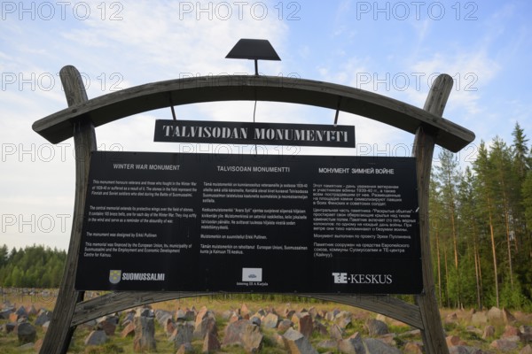 Black memorial plaque for the Winter War Memorial in front of a rocky field and forest, Kotiranta, Ala-Vuokki, Kainuu, Finland