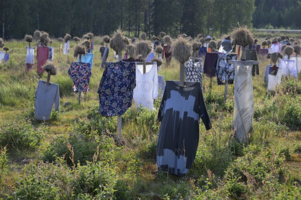 Artwork outdoor installation The silent people of Reijo Kela Straw dolls wear colorful clothes in a field at the edge of the forest, Suomussalmi, Kainuu, FinlandSuomussalmi, Kainuu, Finland
