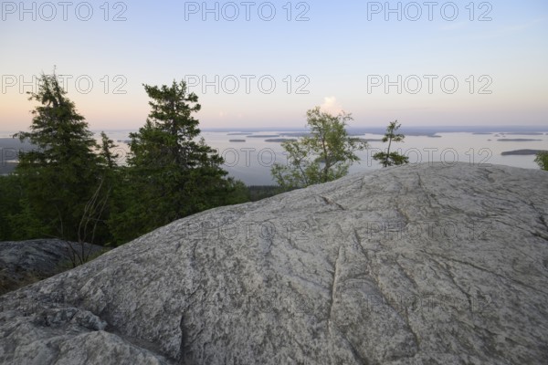 Tranquil view of a lake at dusk with rocks and trees in the foreground, Koliberg, Finland's most famous viewpoint, Ylä-Koli, North Karelia, Finland