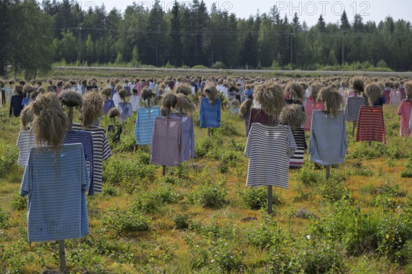 Artwork installation OUThe silent people of Reijo Kela Straw dolls wear colorful clothes in a field at the edge of the forest, Suomussalmi, Kainuu, Finland