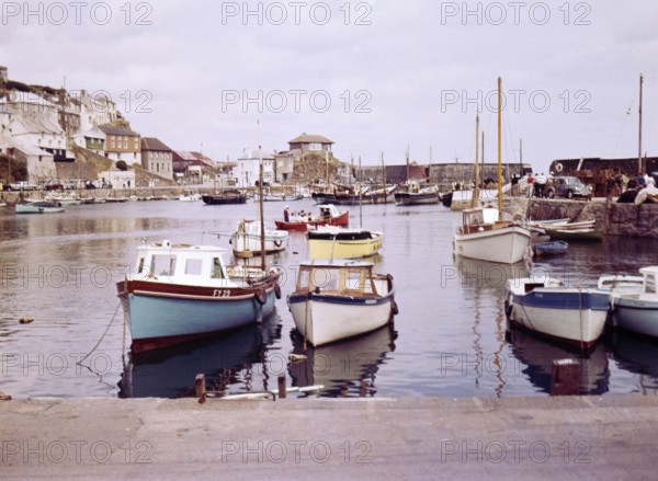 Boats at moorings in the harbour at seaside fishing village of Mevagissey, Cornwall, England, UK c 1960
