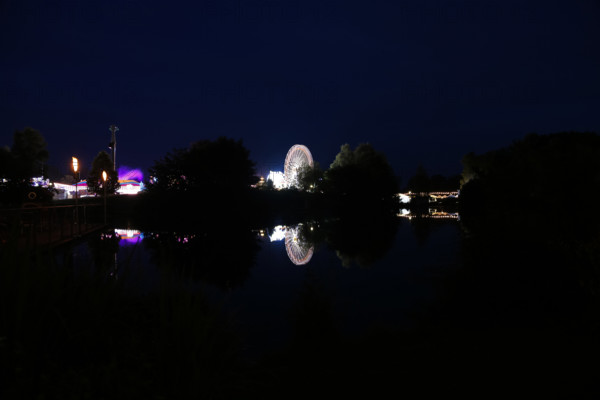 Fairground in Ulm Friedrichsau at night, folk festival, hustle and bustle, fair, Ferris wheel, amusement park, amusement attraction, ride, artificial light, darkness, reflection in natural lake, Ausee, Ferris wheel, Ulm, Baden-Württemberg, Germany