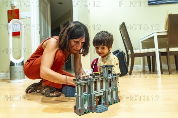 Mother and son enjoying quality time together, building a toy house in the comfort of their living room, fostering creativity and bonding through play