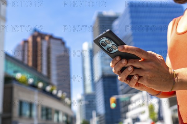 Tourist using a smartphone while surrounded by the vibrant downtown of vancouver, british columbia, with striking skyscrapers rising in the background on a sunny summer day