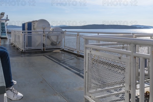 Passenger enjoying the scenic ferry ride from victoria, vancouver island, to vancouver, british columbia, on a bright sunny day with clear blue skies and calm waters