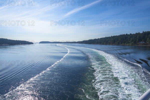 Churning white foam and turquoise water create a scenic wake as a ferry crosses the strait of georgia on a sunny day near vancouver island and vancouver