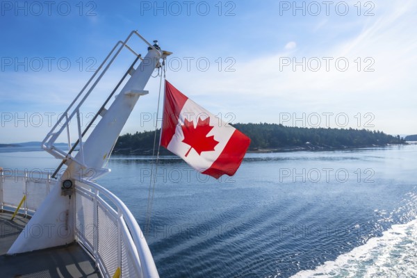 The canadian flag waves proudly from a ferry traveling between victoria on vancouver island and vancouver on the mainland of british columbia, showcasing the beauty of the pacific northwest