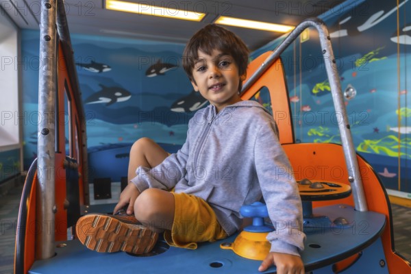 Young boy playing on a colorful play structure aboard a ferry from victoria to vancouver, with a vibrant underwater mural of orcas and marine life in the background