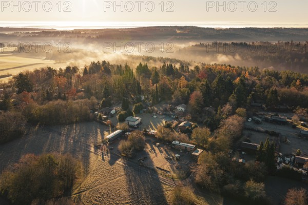 Snowy village surrounded by thick forests with fog and sunrise over the hills, Gechingen, Calw district, Germany