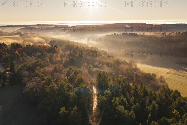 Autumn forests in fog illuminated by the rising sun over the hills, Gechingen, Calw district, Germany