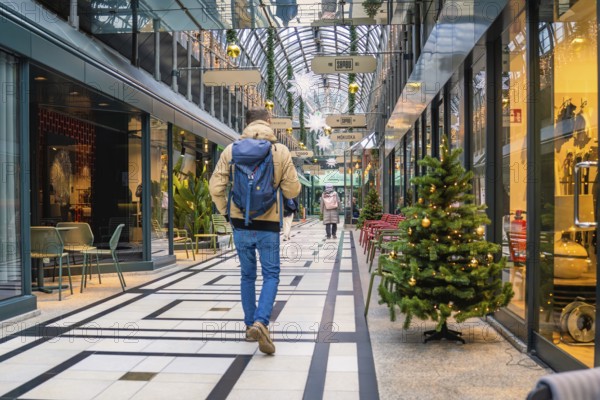Person walking through a festively decorated shopping center with glass roof, Calwer Passage, Stuttgart, Germany