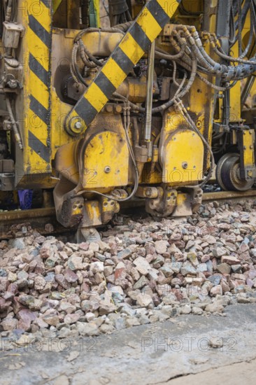 Large construction machine in use. Gravel and yellow-black markings visible, tamping machine on Hermann, Hesse, Bahn, Althengstett, Calw district, Germany
