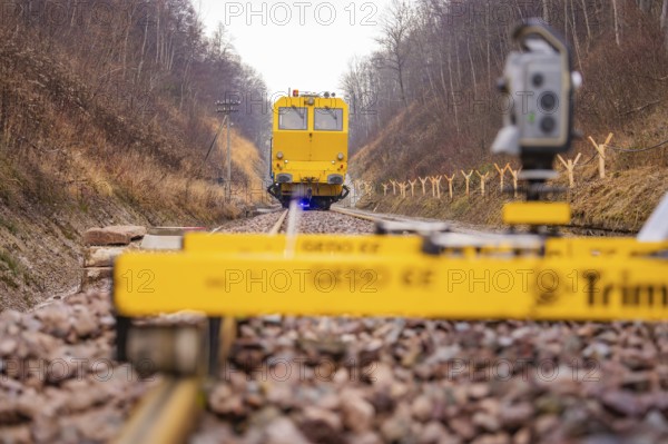 Yellow work machine on railroad track with surveyor in autumn environment, stuffing machine on Hermann, Hesse, railway, Althengstett, Calw district, Germany