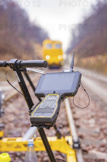 A technical device with a screen in front of a yellow vehicle on the rails, tamping machine on Hermann, Hesse, Bahn, Althengstett, Calw district, Germany