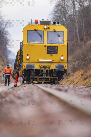Yellow track construction equipment on rail road, worker watching work, stuffing machine on Hermann, Hesse, railway, Althengstett, Calw district, Germany