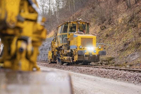 Rail construction machine in use on railroad tracks, indicated blur in the foreground, stuffing machine on Hermann, Hesse, Bahn, Althengstett, Calw district, Germany