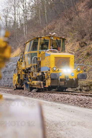 Yellow track construction equipment on tracks with wooded track under construction, tamping machine on Hermann, Hesse, railway, Althengstett, Calw district, Germany