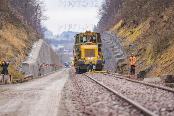 Rail construction machine in the landscape, workers seen along the tracks, tamping machine on Hermann, Hesse, railway, Althengstett, Calw district, Germany