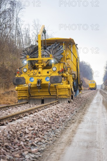 Large yellow track construction machine on railway line in wooded area, tamping machine on Hermann, Hesse, Bahn, Althengstett, Calw district, Germany