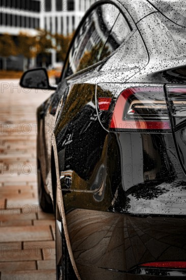 Close-up of a black vehicle with a rain-wet surface in an urban environment, Deer E-Carsharing, Tesla Model 3, Calw, Germany