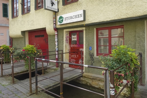 Pub, stork, traditional restaurant, beer pub on the river Ammer, red front door, graffiti, bridge, Tübingen, Baden-Württemberg, Germany