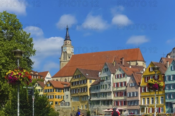 Historic old town, Neckar front, houses, colorful facades, collegiate church, people, cyclists, helmets, left floral decoration on street lamp, colorful blossoms, light, on Neckar, Tübingen, Baden-Württemberg, Germany