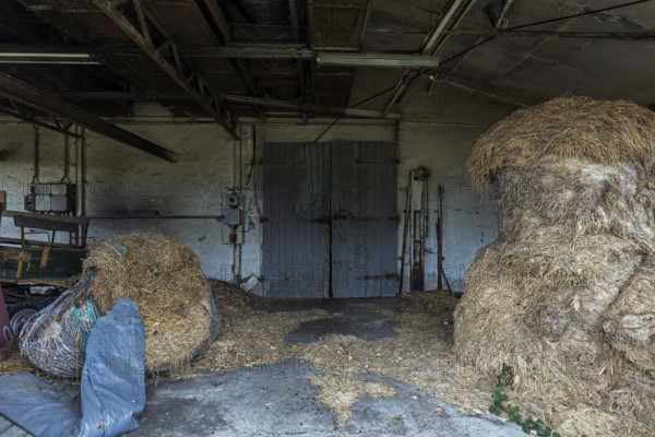 Building with wooden gate and straw bales dilapidated plant of a former agricultural production cooperative of the former GDR, LPG, Lost Place, Müggenburg, Fischland-Darß-Zingst, Western Pomerania Lagoon Area National Park, Mecklenburg-Western Pomerania, Germany