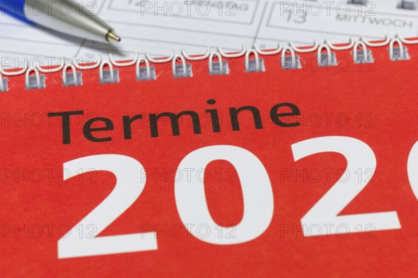 Close-up of a red calendar for 2026 with spiral binding and blue pen, diary