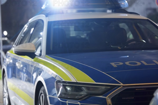 Symbolic image of a police operation: police emergency vehicle with flashing blue lights (digitally enhanced)