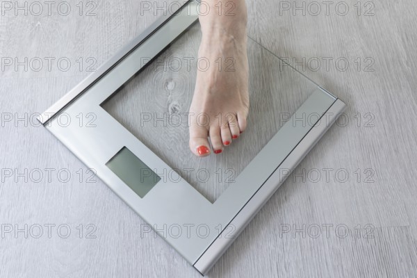 Foot of a woman standing on a digital bathroom scale while monitoring her weight. This scene conveys a sense of health awareness and personal care in everyday life