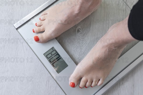 Feet of a woman standing on a digital bathroom scale while monitoring her weight. This scene conveys a sense of health awareness and personal care in everyday life