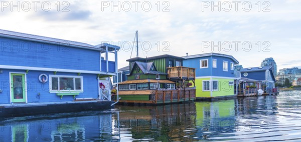 Colorful floating homes reflecting in the calm water in fisherman's wharf park, a popular tourist destination in victoria, british columbia, canada, create a vibrant and picturesque scene