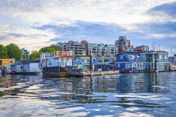 Colorful floating homes reflecting in the calm waters of fisherman's wharf park in victoria, british columbia, create a charming and picturesque scene on a sunny summer day