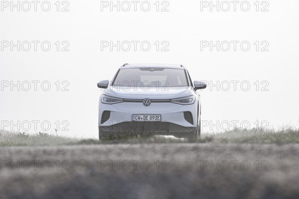 A white car from the front in a foggy, open environment, VW ID4 electric car, Deer Carsharing, Calw, Germany
